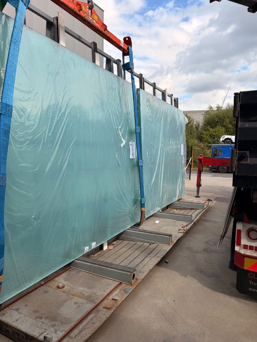 Caisse de verre plat levée par camion-grue avec sangles au dépôt Noxem Group de Mollem